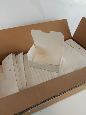 une boîte en carton remplie de feuilles blanches posée sur une table