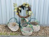 trois paniers en osier garnis de raisins et de feuilles, posés sur du gravier