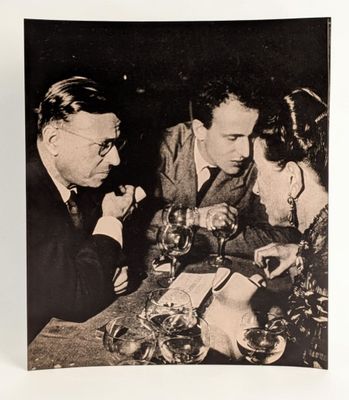 une photo en noir et blanc représentant deux hommes et une femme assis à une table