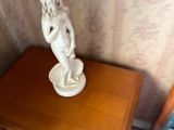 a small table with a statue on it next to a chair