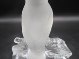 a glass bird sitting on top of a glass plate