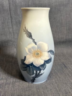 un vase blanc orné d'une fleur sur fond gris