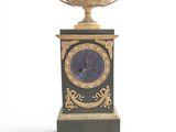 a black and gold clock on a stand with a bowl on top of it