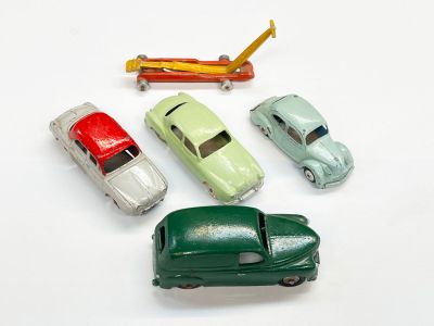 quatre petites voitures et un avion posés sur une surface blanche