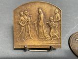 an antique bronze plaque with a woman and two men on it next to a penny