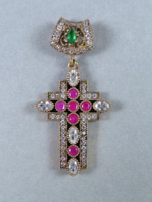un gros plan d'une croix ornée d'une pierre verte et rose