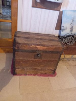 un petit coffre en bois posé par terre à côté d'un miroir
