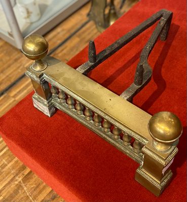 un lit en métal recouvert d'une couverture rouge, posé sur un plancher en bois