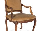 an old wooden chair with a tan upholstered seat