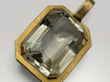 a close up of a gold pendant with a faceted green amethe