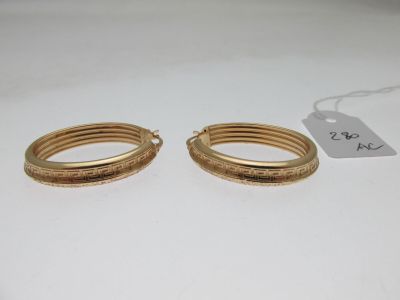 une paire de boucles d'oreilles pendantes dorées ornées de motifs gravés