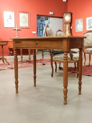des tables et des chaises dans une pièce où est accrochée une horloge au mur