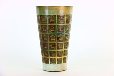 un vase vert orné de motifs, posé sur une table
