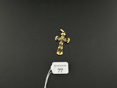 a small gold cross on a black surface next to a tag