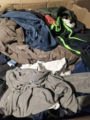 une boîte en carton remplie de vêtements, avec un chat assis dessus