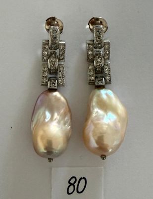 deux paires de boucles d'oreilles en perles et diamants exposées dans une vitrine