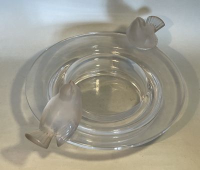 a glass ashtray with a bird on top of it
