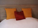 a white bed with two orange pillows on top of it