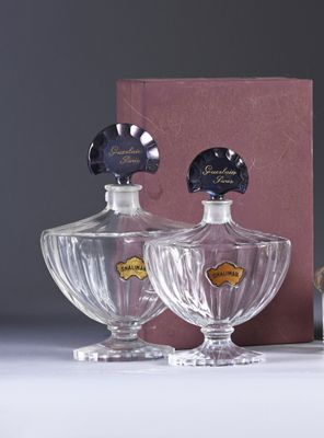 two bottles of perfume sitting on a table next to a box
