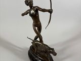 bronze statue of a woman with a bow and arrow on a marble base