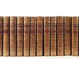 a stack of old books sitting on top of each other on a white surface