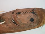 a wooden mask with a long horn on a white surface