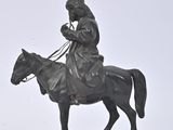 une statue représentant un homme à cheval sur un fond blanc