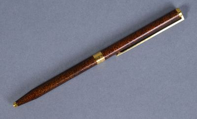 a wooden pen with gold trimming on a blue surface