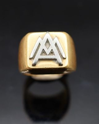 un gros plan d'une bague en or et en argent ornée d'un symbole représentant une montagne