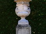 a stone urn sitting in the middle of a lawn