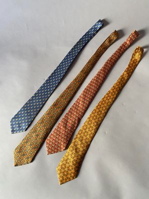 quatre cravates de couleurs différentes sont alignées sur une surface blanche