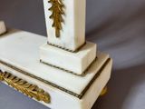 a white vase with a gold decoration on top of it