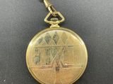 a close up of a gold pocket watch on a chain