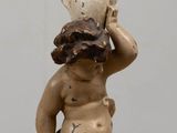 a statue of a baby holding a lamp on top of a table
