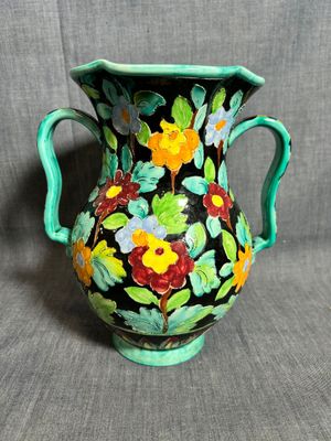 un vase vert orné de fleurs peintes sur fond gris