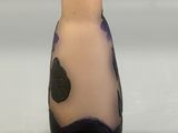purple and black vase sitting on a white surface with a gray background