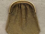 a gold purse with a chain handle on a white surface