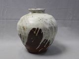 a white and brown vase with two hands painted on it