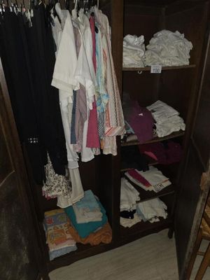 une photo montrant une armoire remplie de vêtements et une chaise