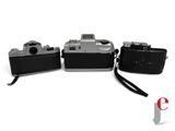 three old cameras sitting next to each other on a white surface