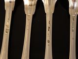 four silver spoons and two silver spoons on a black table