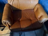 a brown leather chair sitting in a corner of a room