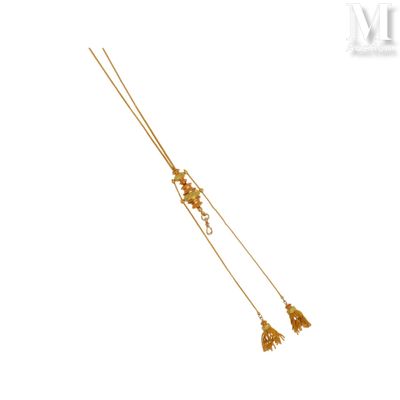 collier plaqué or orné de fleurs et de pompons sur fond blanc