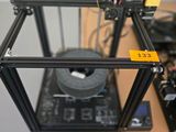 une imprimante 3D posée sur un bureau, à côté d'une imprimante