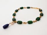 a close up of a bracelet with green beads and a blue bead