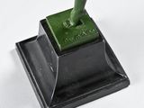 a green statue of a man holding a knife on top of a table