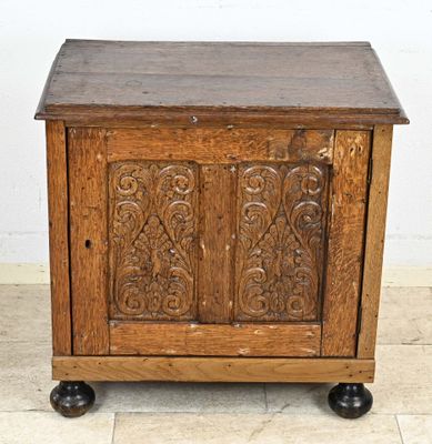 une vieille armoire en bois aux portes sculptées, posée sur un sol carrelé