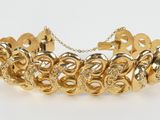 a gold plated bracelet with swirly links and a chain