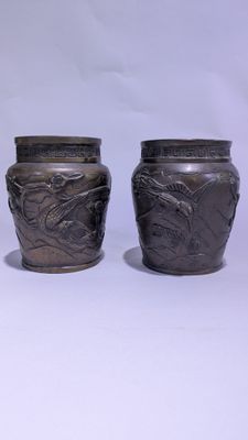 deux vases en argent posés l'un à côté de l'autre sur une surface blanche