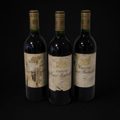 three bottles of red wine sit on a black surface
